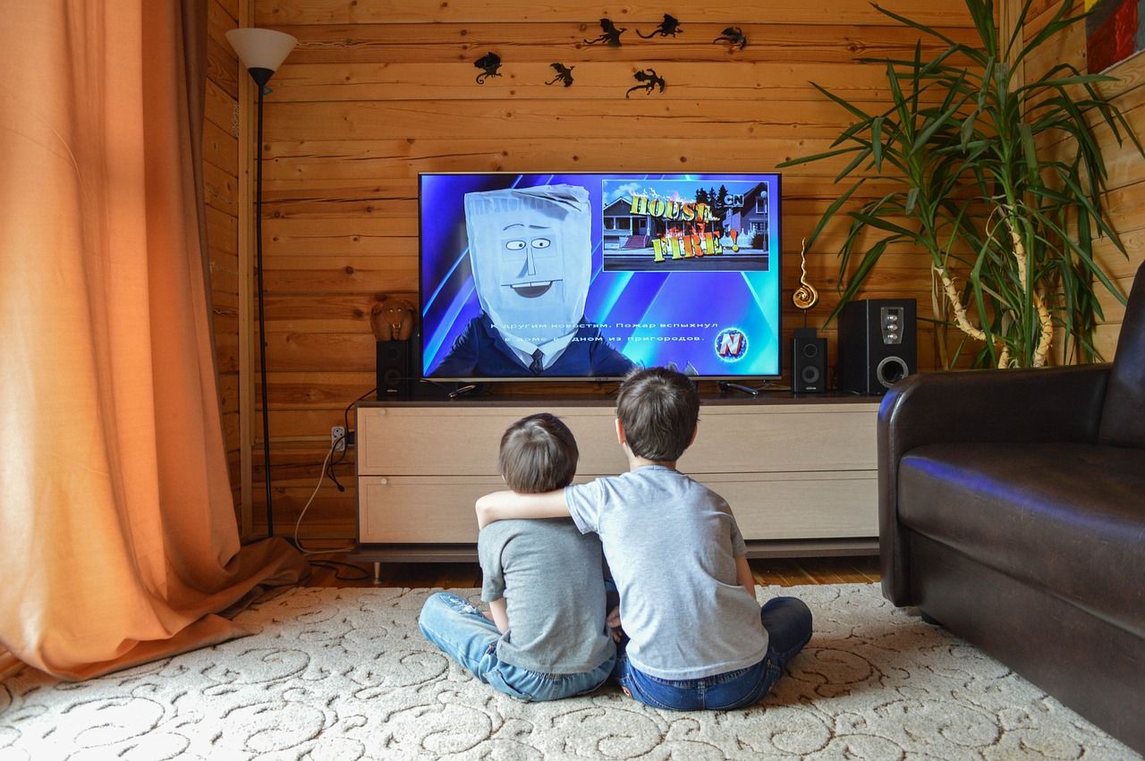 Deux enfants regardent un film sur un écran de télévision